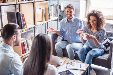 Araçları, fikir paylaşımı, kahve içme ve ofiste çalışırken gülümseyen başarılı genç iş adamları kullanma