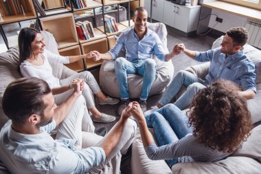 Gençler elele ve gülümseyen daire içinde oturuyor