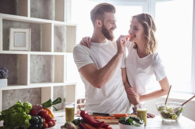 Güzel genç çift evde mutfak sağlıklı yemek pişirme sırasında gülümsüyor
