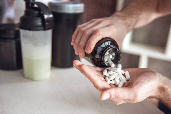 Cropped image of handsome young sportsman preparing sport nutrition in kitchen at home