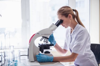 Güzel tıp doktoru laboratuarda mikroskop kullanarak madde eğitimi alıyor