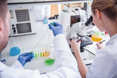 Tıp doktorları laboratuarda test tüpleri ve mikroskop ile çalışıyoruz