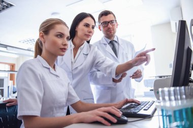 Güzel tıp doktorları laboratuvar test sonuçlarını okurken bir bilgisayar kullanıyor