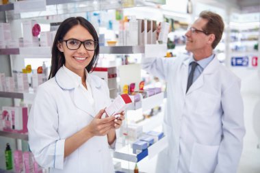 Güzel eczacılar için ilaç arama yapıyor ve eczanede çalışırken gülümseyen