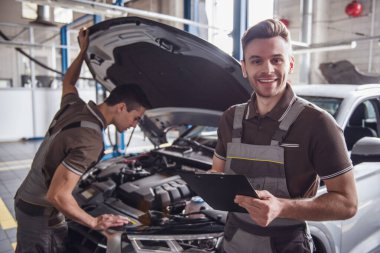 Üniformalı yakışıklı genç otomatik mekanik otomatik hizmetinde çalışırken araba inceliyoruz