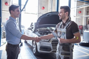 Otomatik hizmetinde. Yakışıklı genç otomatik mekanik üniformalı ve bir istemci el sıkışan ve gülümseyen