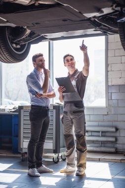 Otomatik hizmetinde. Üniformalı yakışıklı genç otomatik mekanik bir müşteri ile konuşurken ve gülümseyen