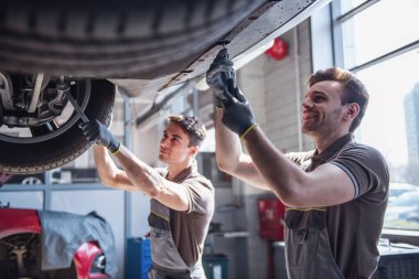 Otomatik hizmetinde. Üniformalı yakışıklı genç otomatik mekanik araba kısayollarımı gülüyorsun