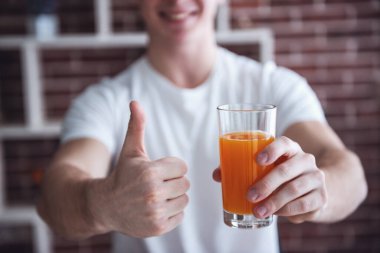 Portakal suyu tutarak, Ok işaret gösteren ve gülümseyen yakışıklı adam Resim kırpılmış