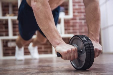 Çıplak gövde evde egzersiz tekerlek ile çalışma dışarı ile yakışıklı kaslı adamın kırpılmış görüntü