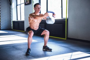 Yakışıklı genç kaslı sporcu kettlebell spor salonunda çalıştığını