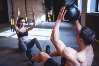 Güzel genç spor çifti jimnastik salonunda sağlık topuyla antrenman yapıyor.