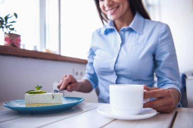 İçme kahve ve tatlı yeme, terasta bir kafede oturan genç güzel kız. Yakın çekim.