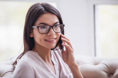 Ev ofis. Oturma odasında kanepede oturan ve telefonda konuşurken başarılı genç güzel kadın