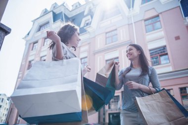 Düşük açılı görünüş alışveriş torbaları holding, söz ve açık havada duran süre gülümseyen güzel kız
