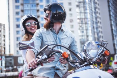 Güzel genç çift güneş gözlüğü ve kask bir scooter sürme sırasında gülümsüyor