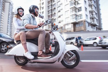Güzel genç çift güneş gözlüğü ve kask bir scooter sürme sırasında gülüyorsun