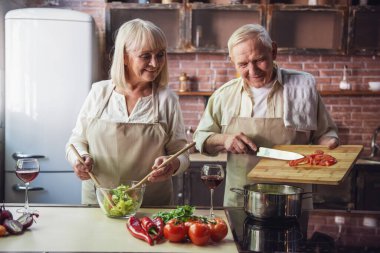 Güzel üst düzey iki önlük içinde konuşmak ve birlikte mutfakta yemek yaparken gülümseyen