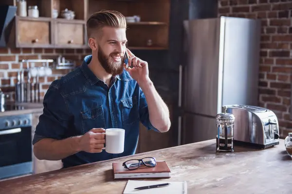 Mobil Telefonda Konuşurken Kahve Içme Mutfakta Istirahat Ederken Gülümseyen Genç — Stok fotoğraf