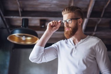 Kameraya gülümseyen bardakları sakallı genç bir adam portresi. Alt görünümü