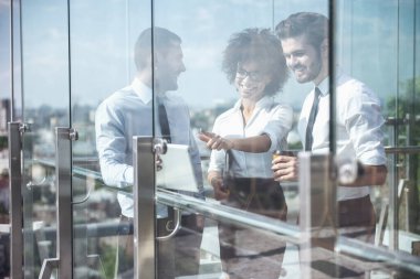Güzel iş adamları konuştuğunuz ve ofis binası kahve tatilinde, balkonda dururken gülümseyen pencereden görüntüleme