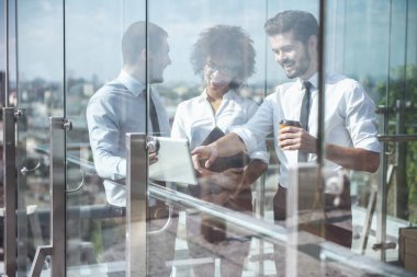 Güzel iş adamları konuştuğunuz ve ofis binası kahve tatilinde, balkonda dururken gülümseyen pencereden görüntüleme