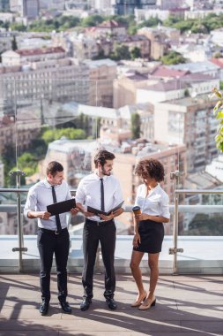 Kahve molası sırasında bina ofis balkonda dururken belgeleri tartışırken güzel iş adamları yüksek açılı görünüş