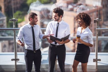 Güzel iş adamları belgeleri tartışmak ve kahve molası sırasında bina ofis balkonda dururken gülümseyen