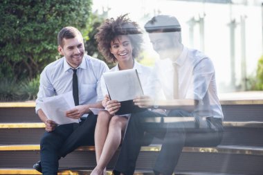 Güzel iş adamları belgeleri tartışmak ve açık havada otururken gülümseyen