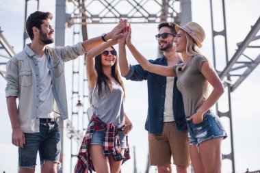 Neşeli genç insanlar yüksek beş veren ve şehirde yürürken gülümseyen