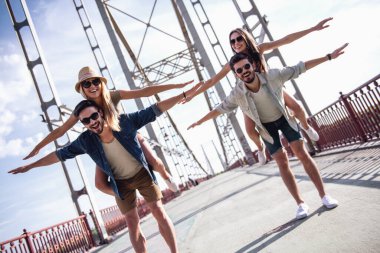 Neşeli genç insanlar kameraya bakıyor ve pickaback oturan kız şehirde yürürken gülümseyen