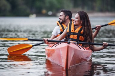 Mutlu genç bir çift deniz yelekler içinde bir kayık yelken gülümsüyor