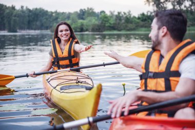 Mutlu genç bir çift deniz yelekler içinde kayaks yelken gülümsüyor