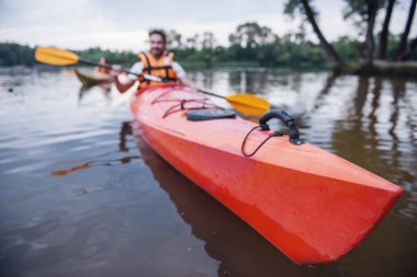 Mutlu genç bir çift deniz yelekler içinde kayaks yelken gülümsüyor