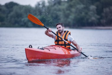 Bir kayık yelken sırasında deniz yeleği yakışıklı genç gülümseyen