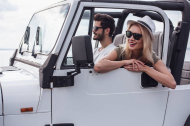 Güzel genç çift güneşli havalarda araba ile seyahat ederken gülümsüyor