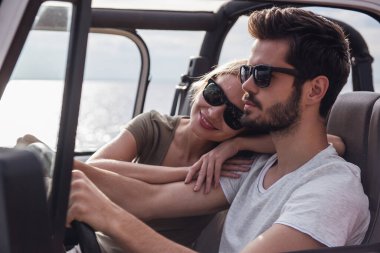 Güzel genç çift güneşli havalarda araba ile seyahat ederken gülümsüyor