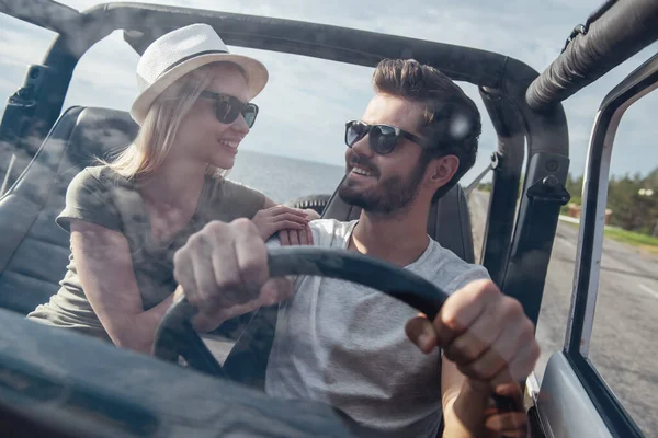 美しい若いカップルが話しているし 天候の良い日に車で旅行しながら笑みを浮かべて — ストック写真