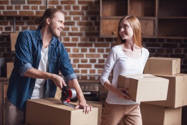 Güzel genç çift karton kutu ambalaj ve yeni daire içine hareket ederken gülümseyen