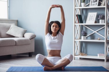 Güzel sporcu kız evde yoga yaparken meditasyon yapıyor.