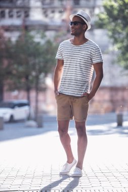 Şehirde yürürken gülümseyen yakışıklı adamın tam boy portresi.