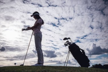 Golf sahasında golf club dururken tutan güzel genç kadın portresi tam uzunlukta