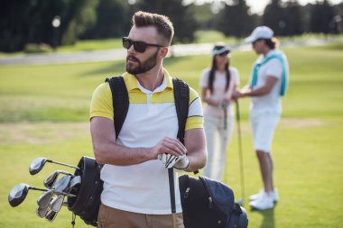Güzel insanlar istirahat ve oynarken golf, yakışıklı olan ön planda