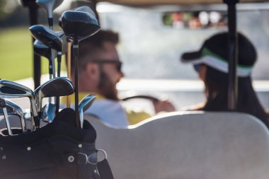 Arkadan görünüşü güzel çift golf kulüpleri odak bir golf arabası sürüş sırasında söz