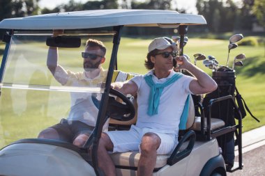 Yakışıklı erkekler bir golf arabası sürüş ve golf delik için arama