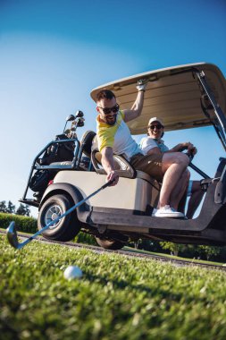 Bir golf arabası sürüş sırasında yakışıklı erkekler gülümseyen, bir adam topu golf kulübünde raising