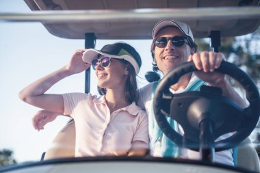 Güzel çift bir golf arabası sürüş sırasında gülümsüyor
