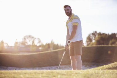 Yakışıklı olan bir golf kulübü golf, güzel güneş parlıyor oynarken kullanıyor