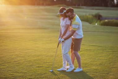 Güzel genç çift sarılma ve golf oynarken gülümseyen