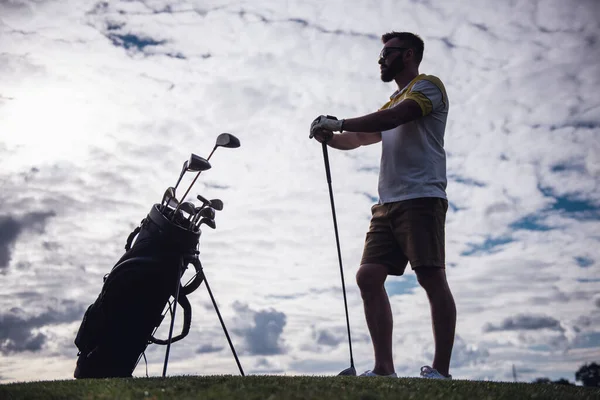 Tam uzunlukta bir golf kulübü tutarak ve uzak duran golf sahası üzerinde seyir yakışıklı adam portresi